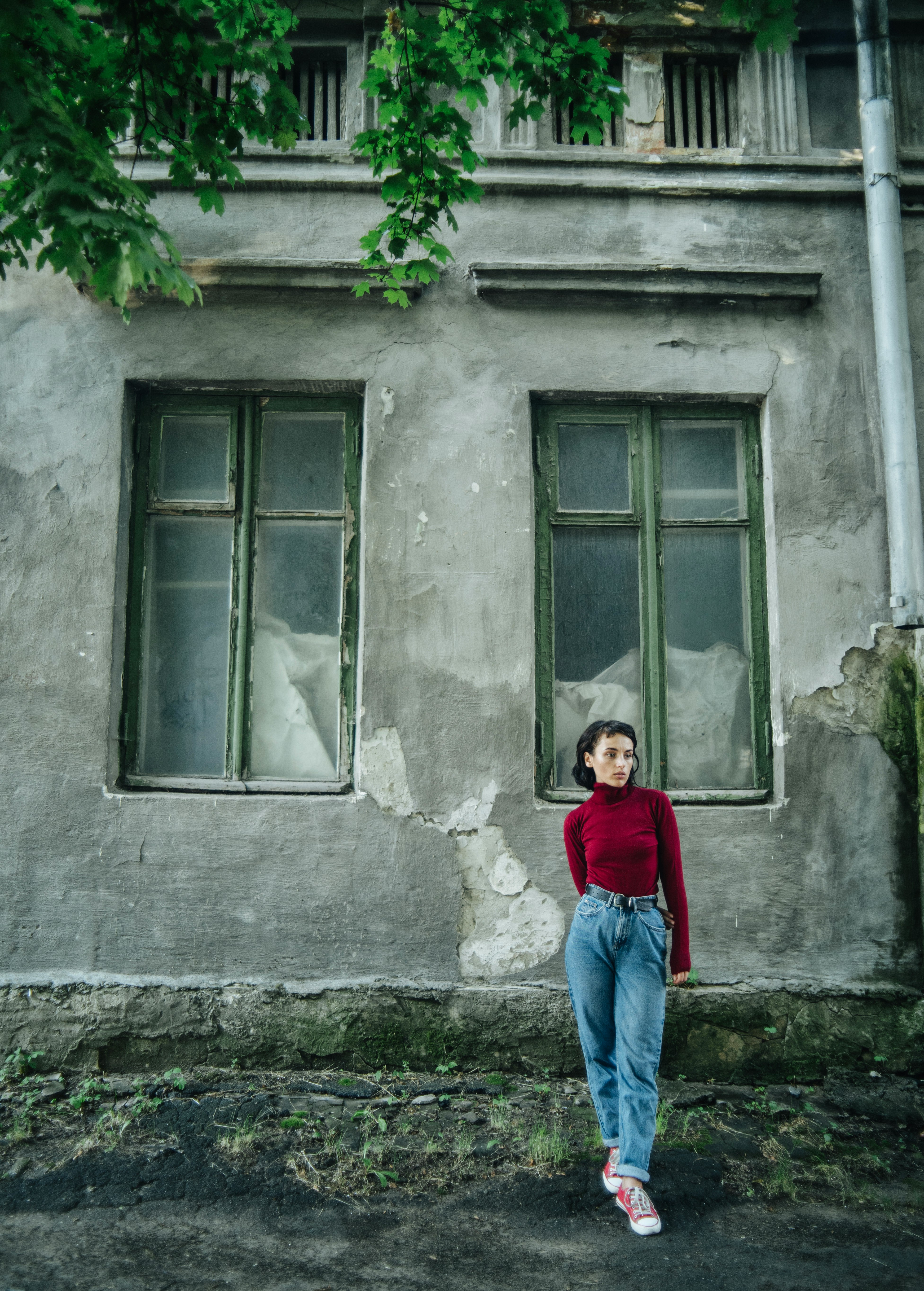 girl in red long sleeve shirt and blue denim jeans standing in front of window